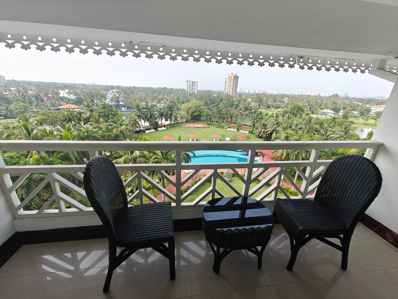 The backwater-view balcony with two chairs and a table, overlooking pool and palms