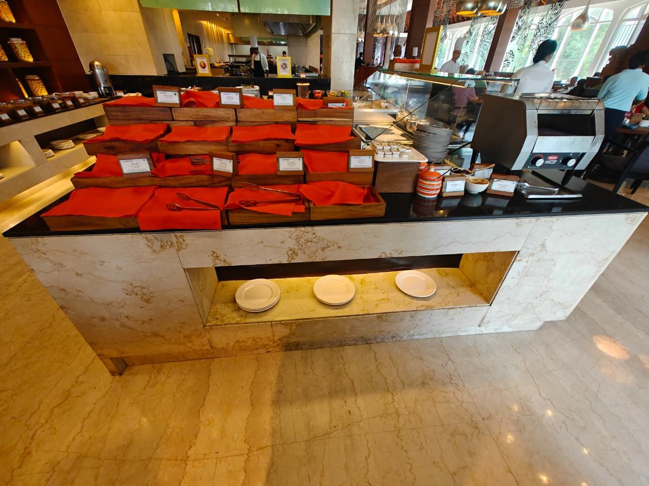 Buffet counter with wooden trays and red napkins beside a live toaster station