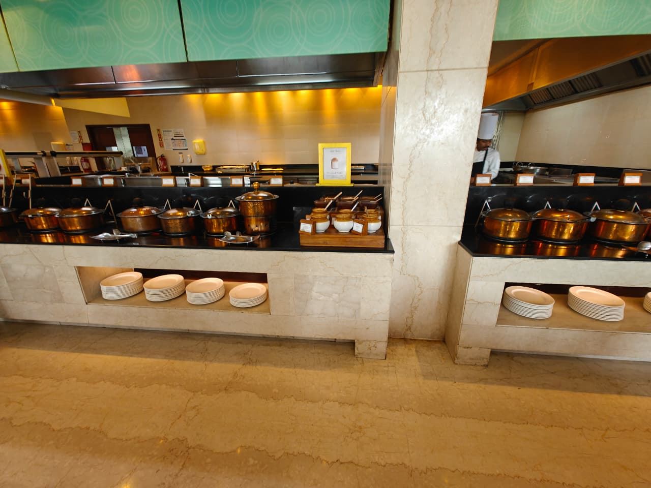 Hot dishes in copper pots at a live cooking station with a chef