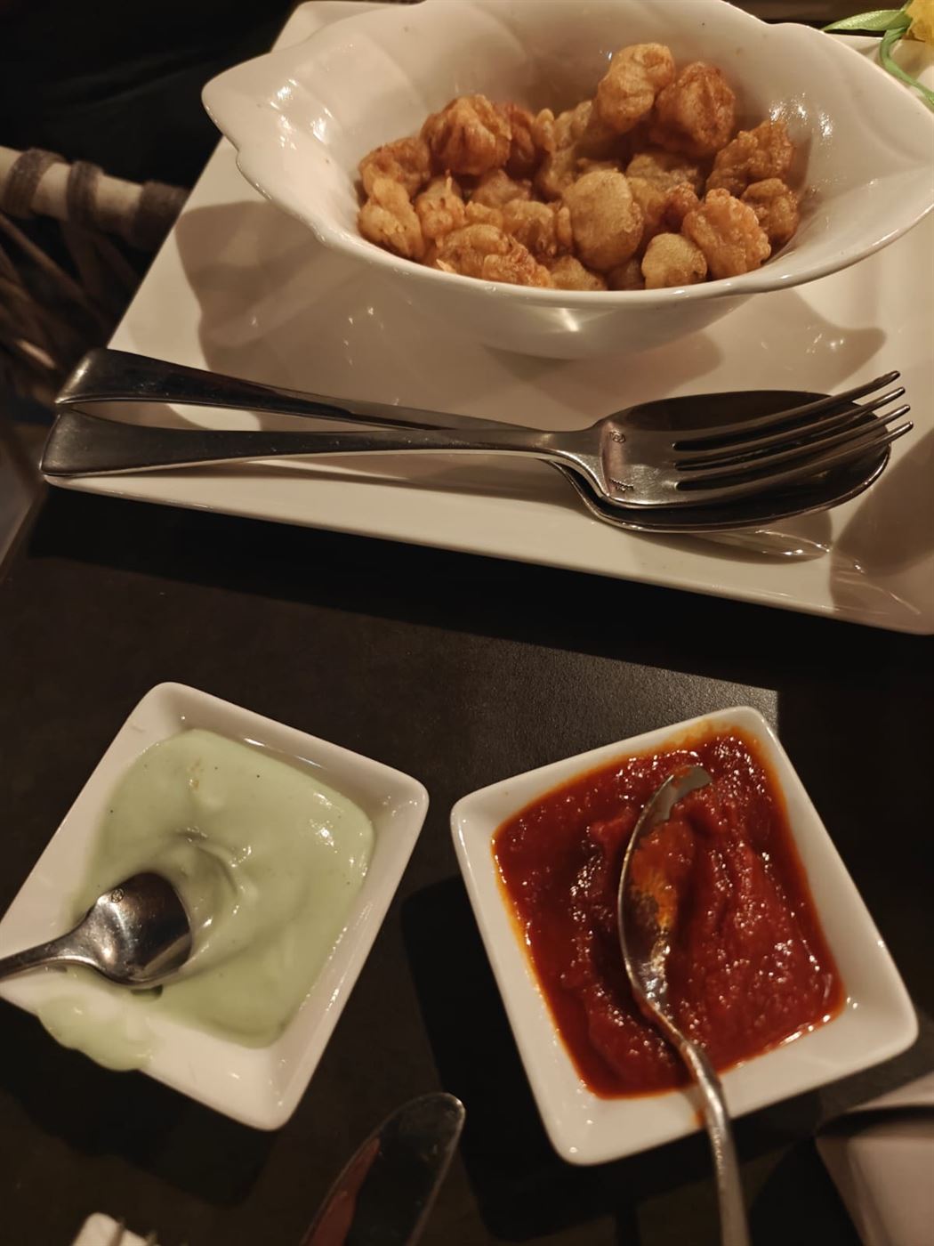 A bowl of fried calamari with two dipping sauces