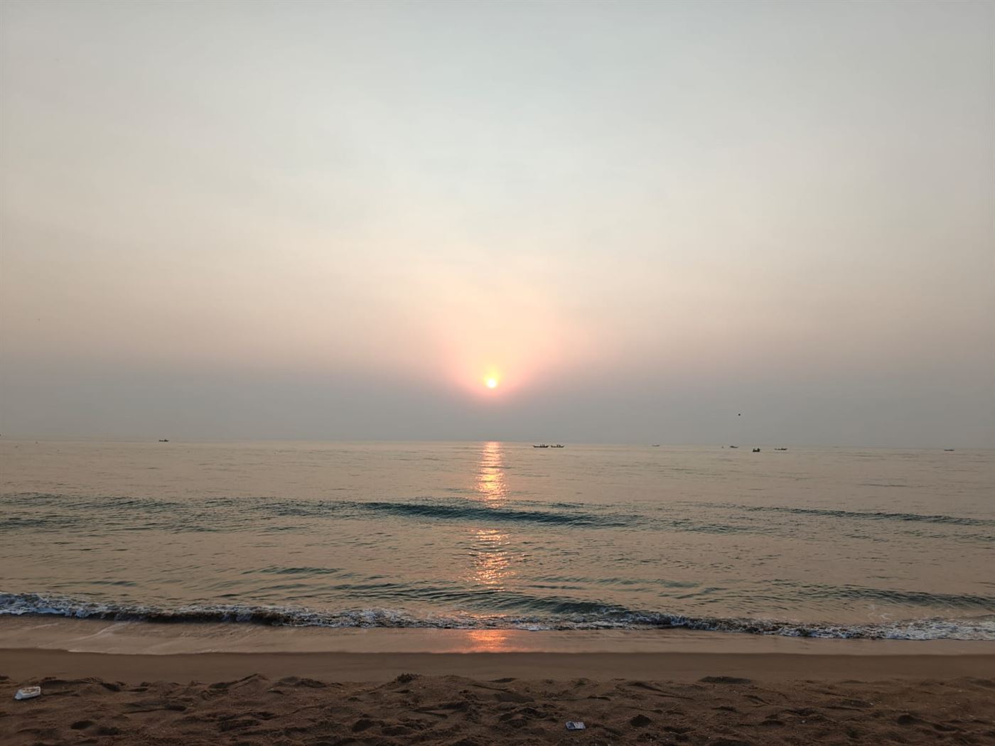 The sun low over the water with waves rolling in