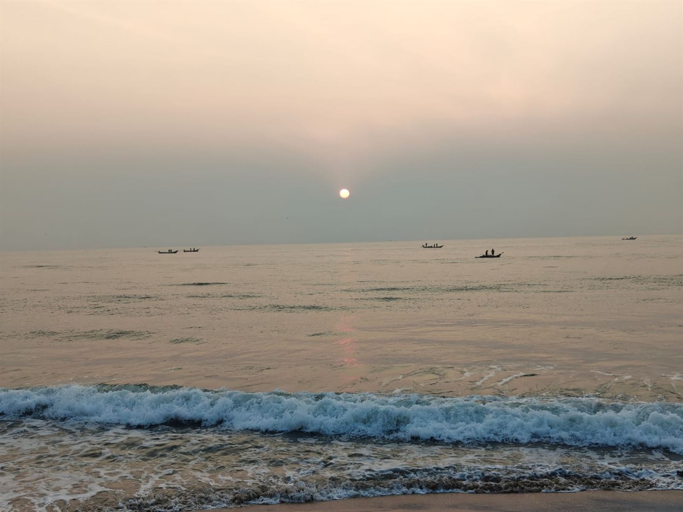 Sunrise over the sea with fishing boats on the horizon