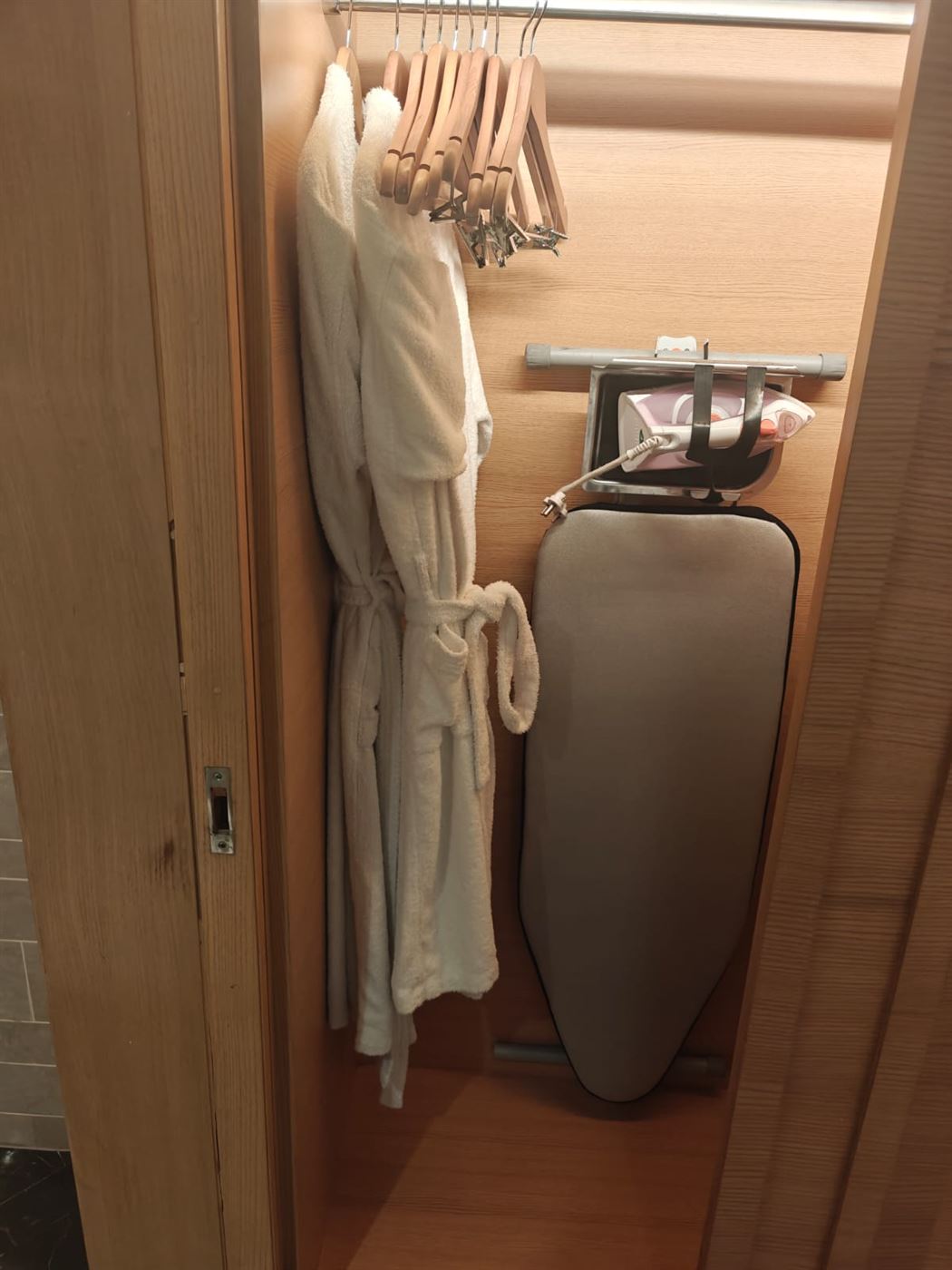 Wardrobe with robes, hangers and an ironing board