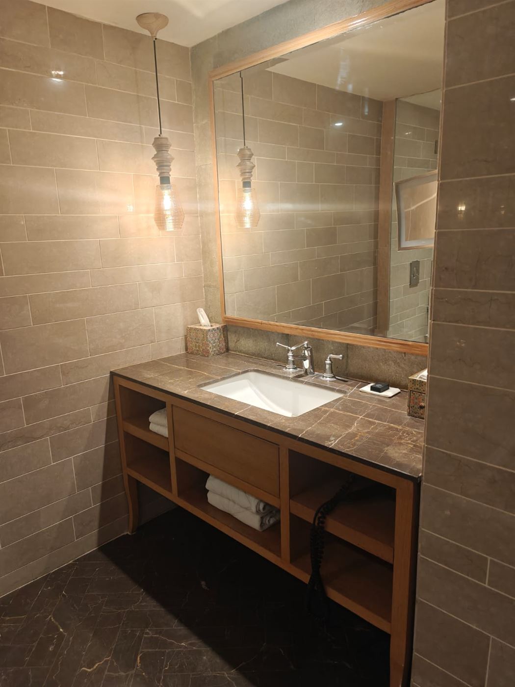 Bathroom vanity in stone and wood with a large mirror