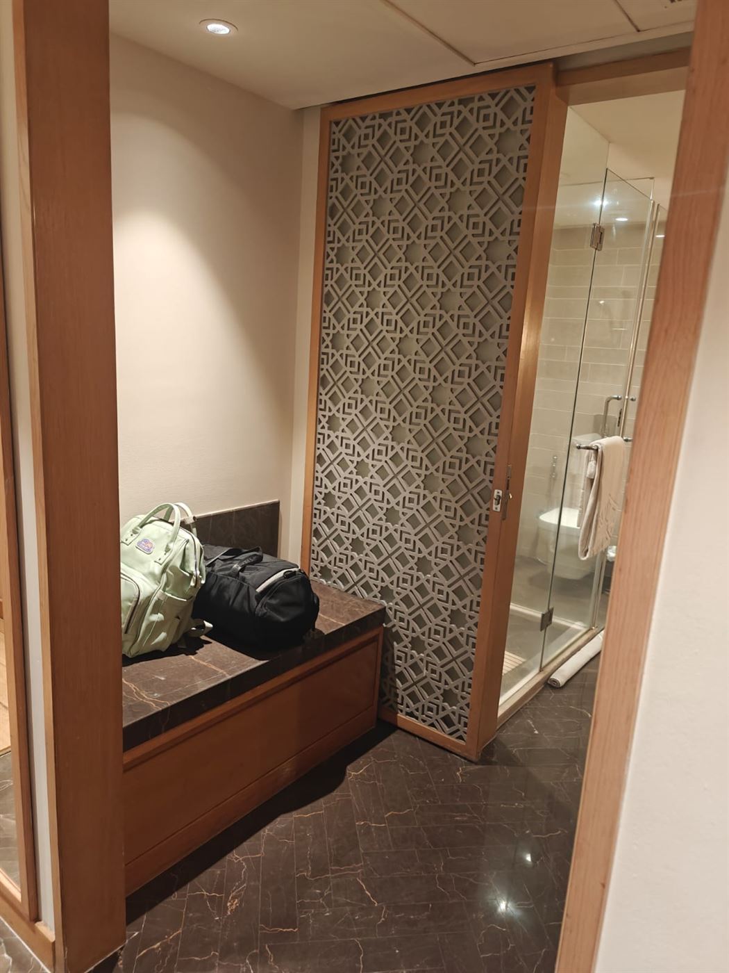 Bathroom entry with a luggage bench and walk-in shower